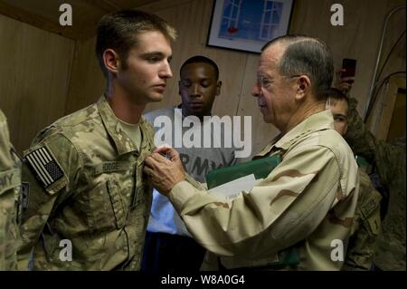 Presidente del Comune di capi di Stato Maggiore Adm. Mike Mullen presenta il cuore viola di U.S. Army Spc. Preston M. Hodge ha a Bagram Air Base, Afghanistan, il 1 agosto, 2011. Hodge ha è stato ferito quando la sua pattuglia montata è venuto sotto le armi leggere e lanciarazzi attacco granata. Mullen è su un corso di cinque giorni OSU tour con il comico Jon Stewart, NBA legend Karl Malone e mago David Blane visitando le truppe in Afghanistan e in Iraq. Foto Stock