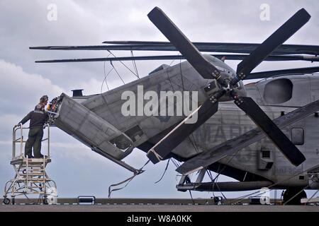 Stati Uniti Marines eseguire la manutenzione su un CH-53E Super Stallion a bordo della USS Makin Island (LHD 8) in corso nell'Oceano Pacifico il 20 dicembre, 2011. La Makin Island è sulla sua implementazione da nubile di condurre le operazioni negli Stati Uniti 7 flotta area di responsabilità. Stati Uniti i marinai e Marines assegnato alla USS Abraham Lincoln, la USS Carl Vinson e la USS Makin Island eseguite diverse operazioni tra dic. 13 e DIC 20, 2011, mentre in corso nell'Oceano Pacifico. Foto Stock