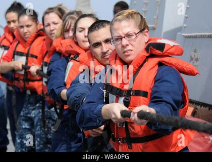 Stati Uniti Navy velisti assegnati alle visite-missile destroyer USS Halsey (DDG 97) heave una linea collegata ad una fascia di sollevamento durante un uomo a mare trapano di recupero in mare Arabico il 24 gennaio, 2012. La Halsey è sulla distribuzione per il Pacifico occidentale Regione. Foto Stock