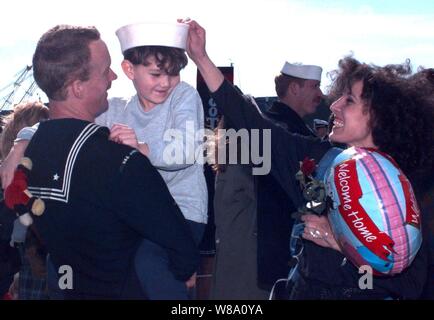 Petty Officer 2a classe Giovanni Neet, U.S. Navy, mantiene il suo figlio Dustin mentre sua moglie Cafada Neet pone il suo husbandХs hat sulla sua testa sonХs il 24 gennaio, 1996. La famiglia era riunita in Norfolk, Virginia, quando Petty Officer NeetХs nave portaerei USS America (CV 66) restituito da un mese a sei, Mare Mediterraneo la distribuzione. Inoltre, l'America Battle Group operati nel mare Adriatico a sostegno della NATO Forza di attuazione (IFOR) in Bosnia ed Erzegovina per il funzionamento uno sforzo congiunto. Questo è stato l'ultimo deployment per la USS America che è pianificata per lo smantellamento dopo th Foto Stock