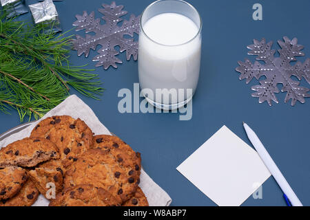 Latte e biscotti al cioccolato e una nota di Babbo Natale Foto Stock