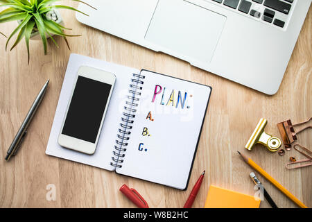 Business plan concetti con Blocco note di carta sul tavolo in legno e i materiali di consumo.piatto design dei laici Foto Stock