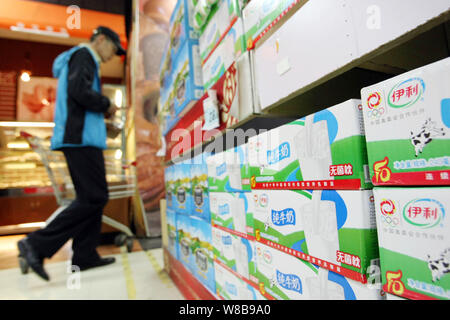 --FILE--un cliente cinese passato passeggiate cartoni di latte Yili al supermercato in Cina a Shanghai, 14 ottobre 2014. Azienda lattiero-casearia Yili era il più popu Foto Stock