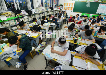 Il cinese agli studenti di esaminare i libri di testo in preparazione al prossimo collegio nazionale esame di ammissione, noto anche come gaokao, nelle loro classi a Fuya Foto Stock