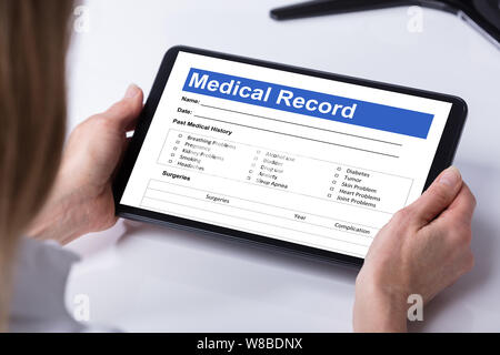 Close-up di medico donna alla ricerca di informazioni paziente forma sulla tavoletta digitale sulla scrivania Foto Stock