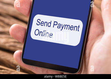 Persona utilizzando Mobilephone per inviare il pagamento on-line Foto Stock