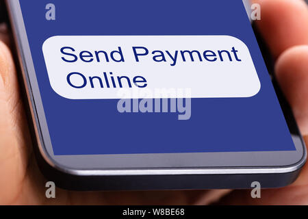 Persona utilizzando Mobilephone per inviare il pagamento on-line Foto Stock