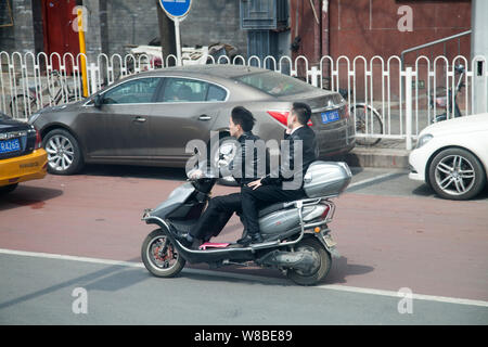 --FILE--ciclisti cinese di cavalcare una bicicletta elettrica su una strada a Pechino in Cina, 13 aprile 2016. Il crescente numero di auto private driver è in contrasto con Foto Stock