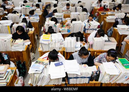 Il cinese agli studenti di esaminare i libri di testo in preparazione al prossimo collegio nazionale esame di ammissione, noto anche come gaokao, nelle loro classi a Gany Foto Stock