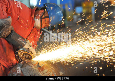 --FILE--un lavoratore cinese lucidi un acciaio prodotto in un impianto siderurgico di Dongbei acciaio speciale Group Co., Ltd. nella città di Dalian, a nord-est della Cina di Liaoning Foto Stock