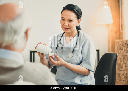 Bella donna con occhi marroni che porta una bottiglia di pillole Foto Stock
