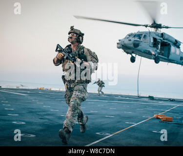 190726-M-HB658-1043 GOLFO ARABICO (26 luglio 2019) una costa Guardsman marittimo con la squadra di risposta di sicurezza ad Est, Advanced Team di interdizione del distacco 1, scorre attraverso il ponte di volo del trasporto anfibio dock nave USS John P. Murtha (LPD 26) durante una visita board ricerca e sequestro esercizio con il raid marittimo vigore, undicesimo Marine Expeditionary Unit (MEU). Il Boxer anfibio gruppo pronto e la XI MEU sono distribuiti negli Stati Uniti Quinta Flotta area di operazioni a sostegno di operazioni navali per garantire stabilità marittimo e la sicurezza nella regione centrale di collegamento del Mediterraneo Foto Stock