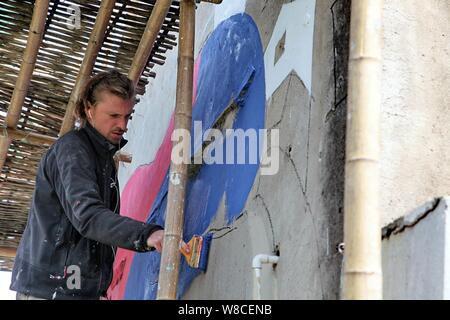 Artista francese Julien Seth Malland vernici su una parete di una casa di Xinyi villaggio di Fengjing città nel distretto di Jinshan, Shanghai, Cina, 13 aprile 2015. Foto Stock