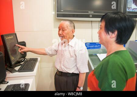 Il 97-anno-vecchio magazzino cinese investor Shi Kunsen, sinistra, colloqui con un altro partecipante a uno stock brokerage house di Hangzhou, a est della Cina di Zhejiang pr Foto Stock