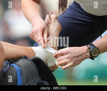 Chiusura del fisioterapista bendaggio di avvolgimento su una ferita al piede della British giocatore di tennis Johanna Konta durante 2019 campionati di Wimbledon, Londra, Engla Foto Stock