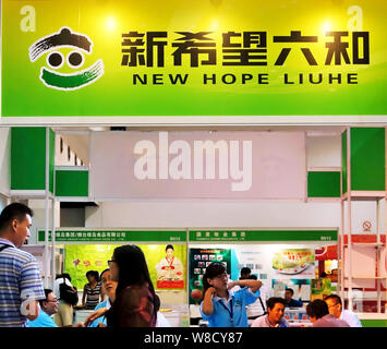 --FILE--dipendenti parla con i visitatori allo stand di cinese alimentazione animale maker nuova speranza Liuhe in una mostra a Shanghai in Cina, 6 settembre 2012. Foto Stock