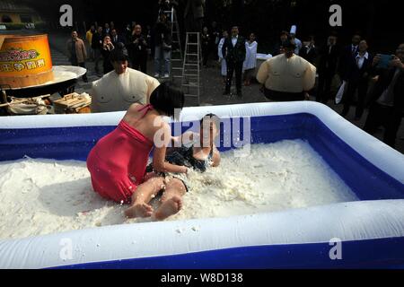 Turisti femmina di partecipare a un concorso di wrestling in un pool gonfiato riempito con tofu e latte presso il vulcanico Hot Spring Resort in Fogang county, Foto Stock