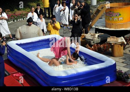 Turisti femmina di partecipare a un concorso di wrestling in un pool gonfiato riempito con tofu e latte presso il vulcanico Hot Spring Resort in Fogang county, Foto Stock