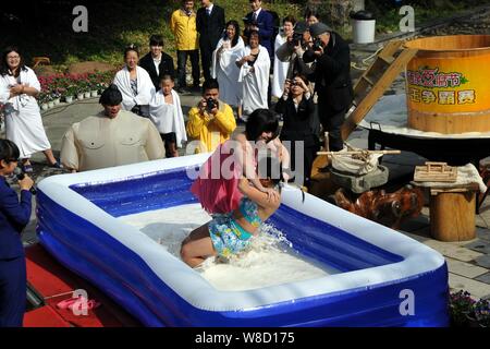 Turisti femmina di partecipare a un concorso di wrestling in un pool gonfiato riempito con tofu e latte presso il vulcanico Hot Spring Resort in Fogang county, Foto Stock