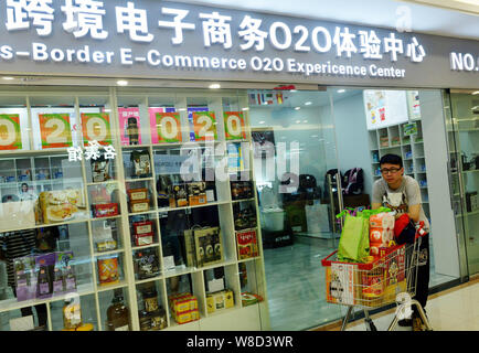 --FILE--un cliente spinge un carrello pieno di shopping nella parte anteriore di un cross-border e-commerce O2O centro di esperienza in Hangzhou, est della Cina di Zhejiang pro Foto Stock