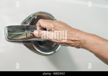Donna anziana lato di apertura della porta per auto Foto Stock