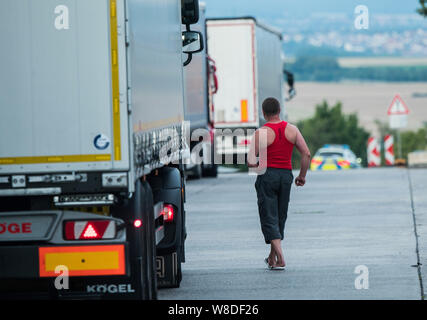 08 agosto 2019, Assia, Ober-Mörlen: un camionista passa il suo veicolo. Hesse autostrade della mancanza di centinaia di camion di spazi di parcheggio. Truck driver quindi girare per arresto di emergenza o di alloggiamenti per le entrate e le uscite al fine di park e a rispettare i loro periodi di riposo. (A dpa messaggio 'Carrello spazi di parcheggio sulle autostrade regolarmente sovraccaricato') Foto: Andreas Arnold/dpa Foto Stock