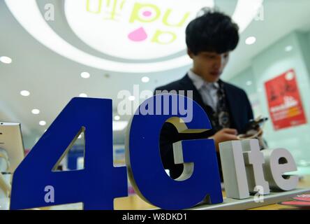 --FILE--un cliente cinese tenta di eseguire uno smartphone supportati da 4G LTE reti di China Mobile in corrispondenza di un ramo di China Mobile in Hangzhou, est mento Foto Stock