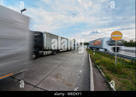 08 agosto 2019, Assia, Ober-Mörlen: LKW's park nella strada di accesso al Wetterau Ost area di servizio. Hesse autostrade della mancanza di centinaia di camion di spazi di parcheggio. Truck driver quindi girare per arresto di emergenza o di alloggiamenti per le entrate e le uscite al fine di park e a rispettare i loro periodi di riposo. Foto: Andreas Arnold/dpa Foto Stock