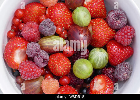 Appena raccolto bacche organiche in bianco ciotola, closeup vista superiore Foto Stock