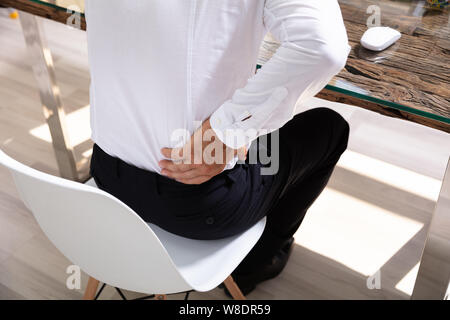 Imprenditore che soffrono di dolori alla schiena a scrivania da ufficio Foto Stock