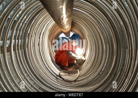 --FILE--un lavoratore cinese lucidi rotoli di tubi in acciaio a un impianto di Dongbei acciaio speciale Group Co., Ltd. nella città di Dalian, a nord-est della Cina di Liaoning Foto Stock