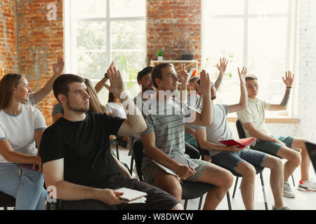 Altoparlante maschio dando una presentazione in sala al workshop per università. Pubblico o sala conferenze. Gli studenti chiedono una domanda, guardano interessate da. Convegno scientifico caso, formazione. L'istruzione. Foto Stock