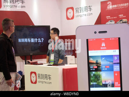 --FILE--un dipendente cinese di colloqui con un visitatore presso lo stand di online autonoleggio service provider o Yongche.com Yidao Yongche durante il 2014 Global Foto Stock