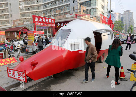 Pedoni guarda l'elicottero in casa a forma di veicolo costruito da pensionato ingegnere cinese Yuan Jingying su una strada nella città di Zhengzhou, la Cina centrale' Foto Stock