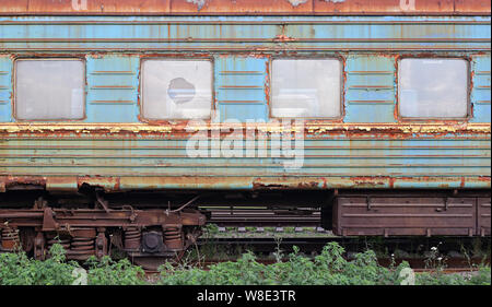Trasporti - Vista laterale sulla ferrovia vecchio arrugginito gettato auto con i vetri rotti. Foto Stock