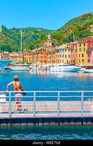 Portofino, Italia - Luglio 1, 2019: donna non identificato sulla banchina a guardare il porto e la città di Portofino, Liguria Foto Stock