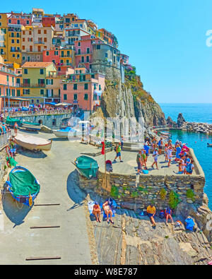 Manarola, La Spezia, Italia - Luglio 2, 2019: Waterfront con persone di appoggio a Manarola piccola cittadina sulla soleggiata giornata estiva, Cinque Terre Foto Stock