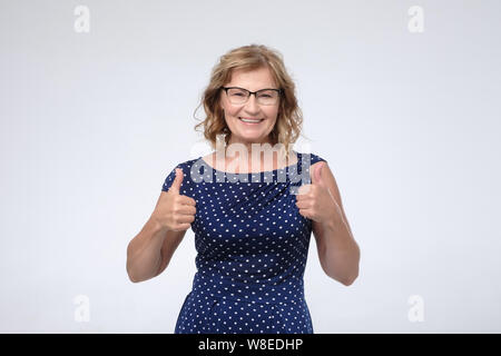 Sorridente bella donna matura che mostra pollice in alto Foto Stock