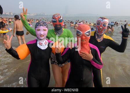 Femmina nuotatori cinesi indossando facekinis con disegni di tradizionale Opera di Pechino pongono in un villaggio su una spiaggia di Qingdao City, est della Cina di Shandong Foto Stock