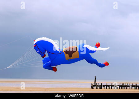 Il kite gonfiabile del cavallo blu volante a Lytham St Annes sul mare. Meteo Regno Unito. Agosto, 2019 forti venti per il week-end Kite Festival a Lytham che è stato ufficialmente annullato a causa di condizioni meteorologiche avverse, e che è stato riprogrammato per settembre. Le squadre del Kuwait già con sede nella città balneare prendono il loro cavallo di galopping di Peter Lynn, il cavallo di carousel o il aquilone di Pegasus prendono all'aria per godere del tempo di volo prima che le condizioni deteriorino. Animali Kites contro il cielo scuro sulla costa Fylde. Foto Stock