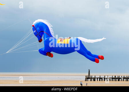 Il kite gonfiabile del cavallo blu volante a Lytham St Annes sul mare. Meteo Regno Unito. Agosto, 2019 forti venti per il week-end Kite Festival a Lytham che è stato ufficialmente annullato a causa di condizioni meteorologiche avverse, e che è stato riprogrammato per settembre. Le squadre del Kuwait già con sede nella città balneare prendono il loro cavallo di galopping di Peter Lynn, il cavallo di carousel o il aquilone di Pegasus prendono all'aria per godere del tempo di volo prima che le condizioni deteriorino. Animali Kites contro il cielo scuro sulla costa Fylde. Foto Stock