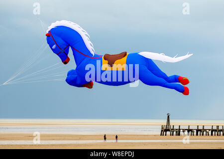 Il kite gonfiabile del cavallo blu volante a Lytham St Annes sul mare. Meteo Regno Unito. Agosto, 2019 forti venti per il week-end Kite Festival a Lytham che è stato ufficialmente annullato a causa di condizioni meteorologiche avverse, e che è stato riprogrammato per settembre. Le squadre del Kuwait già con sede nella città balneare prendono il loro cavallo di galopping di Peter Lynn, il cavallo di carousel o il aquilone di Pegasus prendono all'aria per godere del tempo di volo prima che le condizioni deteriorino. Animali Kites contro il cielo scuro sulla costa Fylde. Foto Stock
