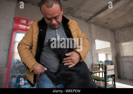 Ex milionario cinese uomo Wang Yan (maschio) i tratti di un cane che è stato salvato per mezzo di lui dal macello al suo animale centro di salvataggio in Changchun c Foto Stock