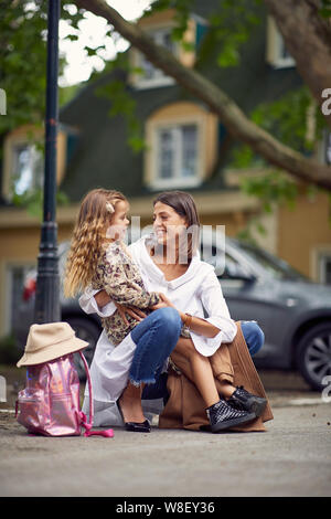 Dopo il primo giorno di scuola, ragazza dire alla mamma come è stato nella scuola Foto Stock