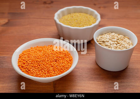 Tre bianchi bocce di materie di legumi , lenticchie rosse, bulgur, scaglie di quercia . Foto Stock