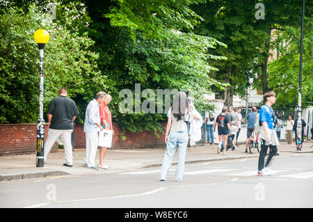 I turisti seguendo le orme dei Beatles sul passaggio pedonale di fronte a studi di registrazione di Abbey Road. Foto Stock