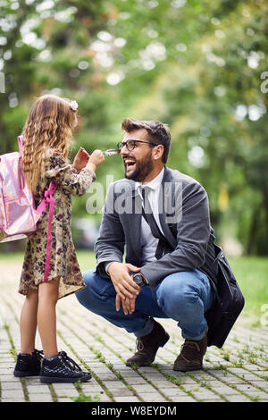 Papà sorridente giocare nel parco con la sua little schoolgirl Foto Stock