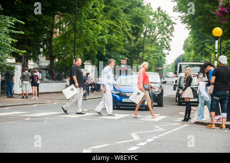 I turisti seguendo le orme dei Beatles sul passaggio pedonale di fronte a studi di registrazione di Abbey Road. Foto Stock