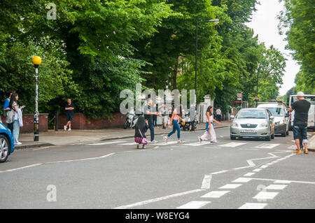 I turisti seguendo le orme dei Beatles sul passaggio pedonale di fronte a studi di registrazione di Abbey Road. Foto Stock