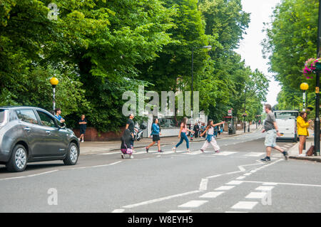 I turisti seguendo le orme dei Beatles sul passaggio pedonale di fronte a studi di registrazione di Abbey Road. Foto Stock